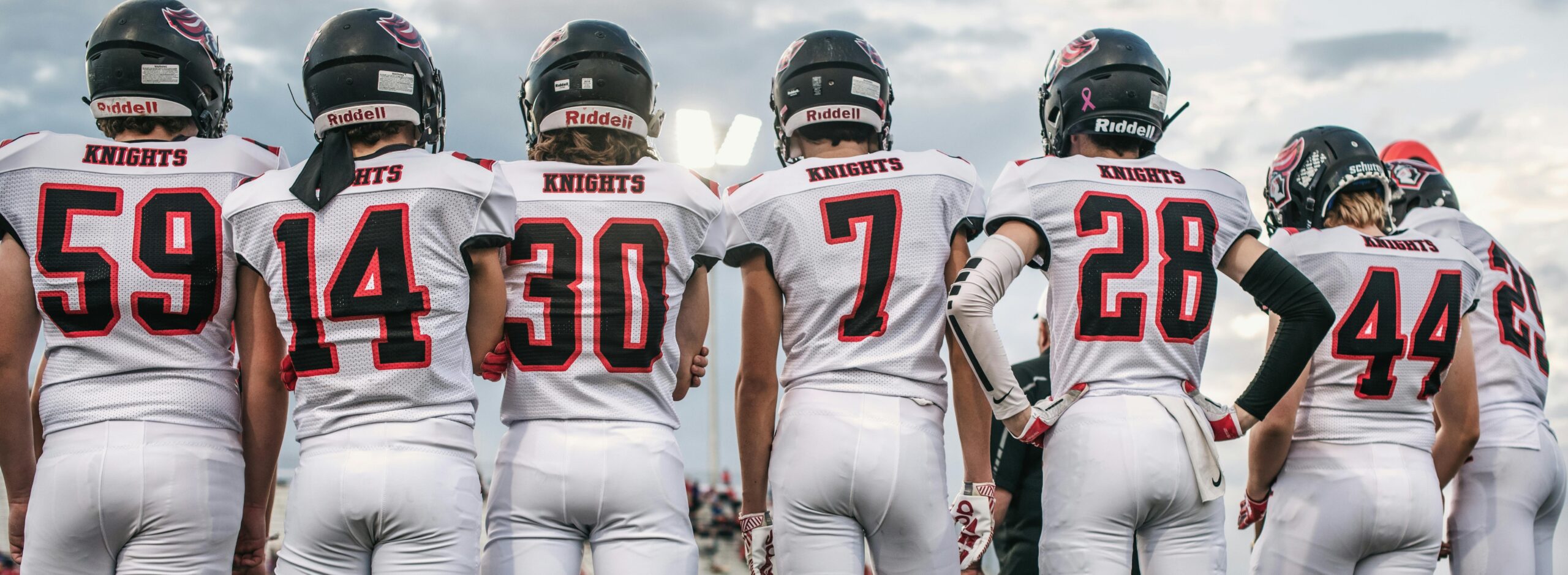 Custom Football Cards by NCASE CARDS. Football players on the sideline during a football game wearing full uniforms and helmets.