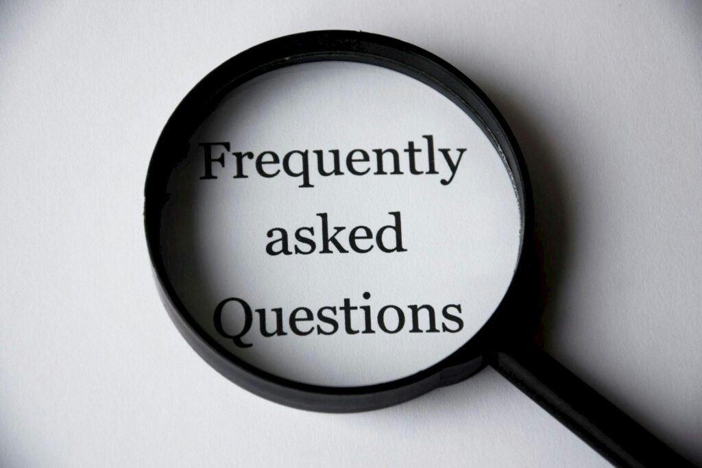 A photo of a black magnifying glass laying over the words "Frequently asked questions" on a white background